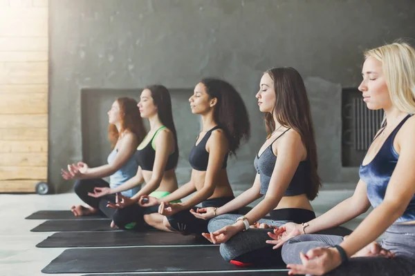 Giovani donne in classe di yoga, rilassarsi posa meditazione — Foto Stock