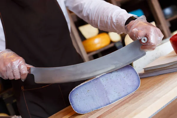 Cutting gouda pesto blue cheese in grocery shop — Stock Photo, Image