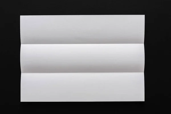 Wit gevouwen vel papier op zwarte achtergrond — Stockfoto