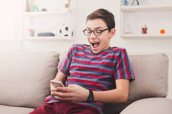 Upphetsad tonårspojke spela mobila spel hemma — Stockfoto