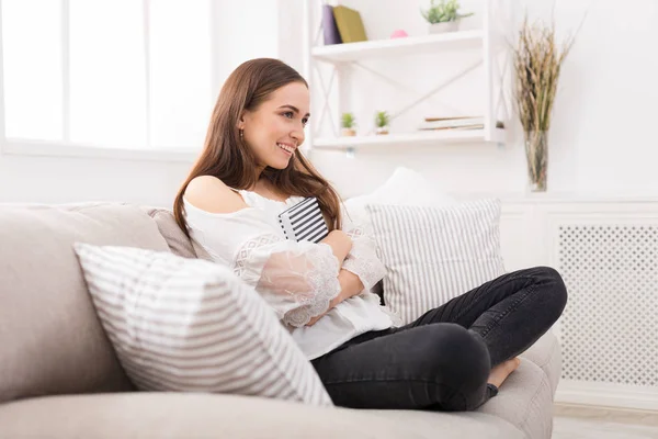 Junge lächelnde Frau sitzt auf Couch — Stockfoto