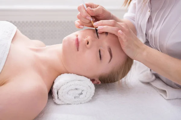 Woman gets eyelashes tinting by beautician at spa — Stock Photo, Image