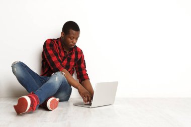 Siyah adam stüdyo katta oturan dizüstü kullanarak konsantre