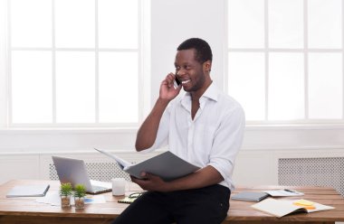 Genç işadamı okuma belgeleri siyah ve mobil modern beyaz ofisinde konuşmak