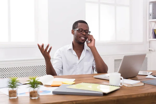 Young black businessman call mobile phone in modern white office