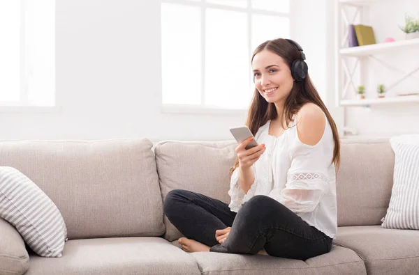 Chica joven en auriculares con móvil — Foto de Stock