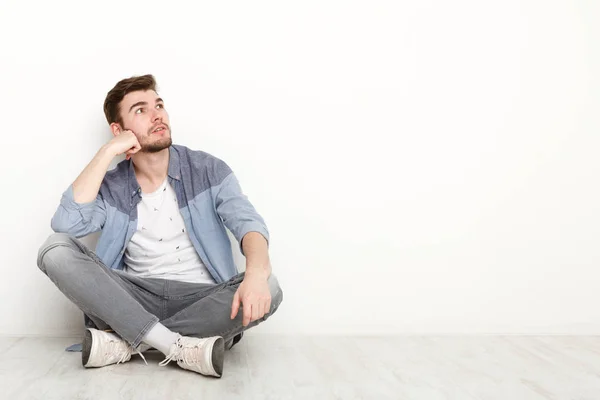 Nachdenklicher Mann sitzt auf dem Boden und blickt nach oben — Stockfoto