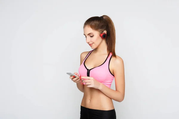 Fitness flicka i hörlurar väljer musik på telefon — Stockfoto