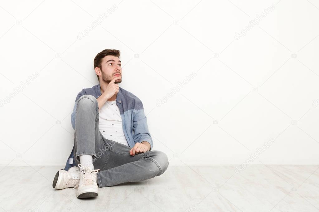 Pensive man sitting on floor and looking upwards