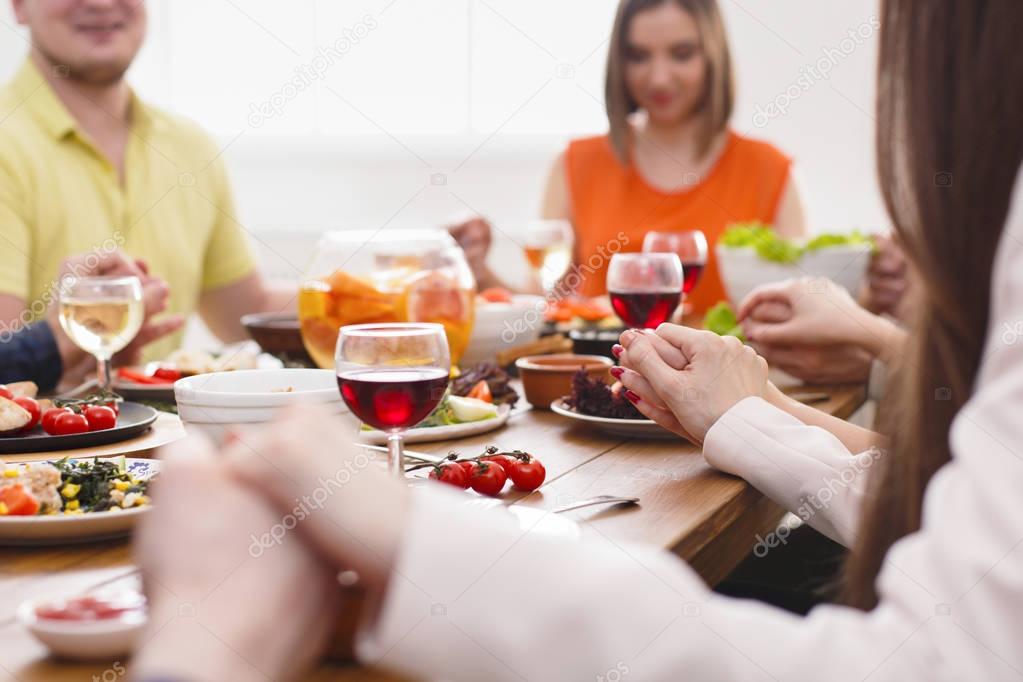 People holding hands praying at dinner table