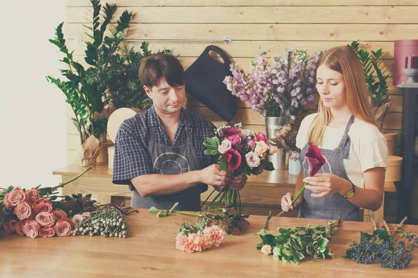 Florist and assistant in flower shop delivery make rose bouquet