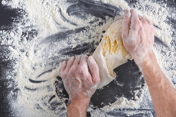 Hands top view knead dough on black background
