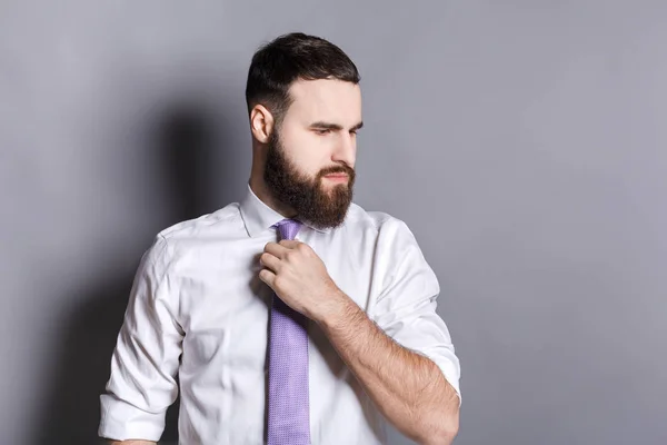 Handsome bearded businessman adjusting his tie — Stock Photo, Image
