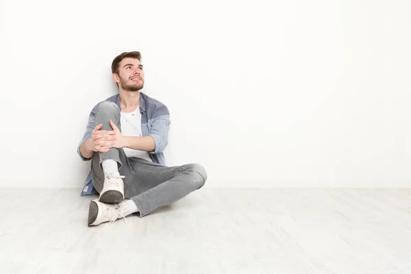 Nachdenklicher Mann sitzt auf dem Boden und blickt nach oben — Stockfoto