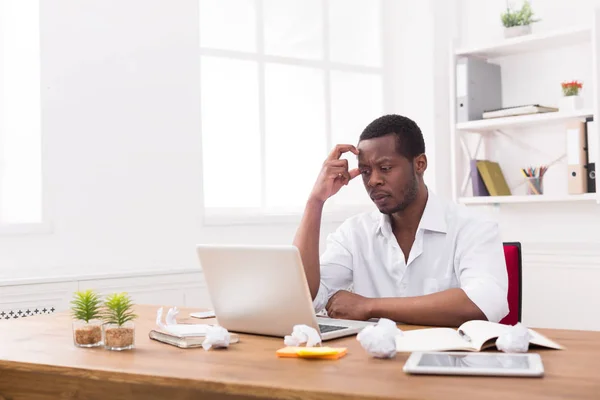 Empleado africano-americano cansado en la oficina, trabajo con el ordenador portátil —  Fotos de Stock