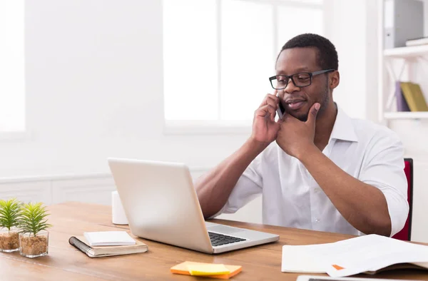 Jonge zwarte zakenman met mobile in moderne witte kantoor — Stockfoto