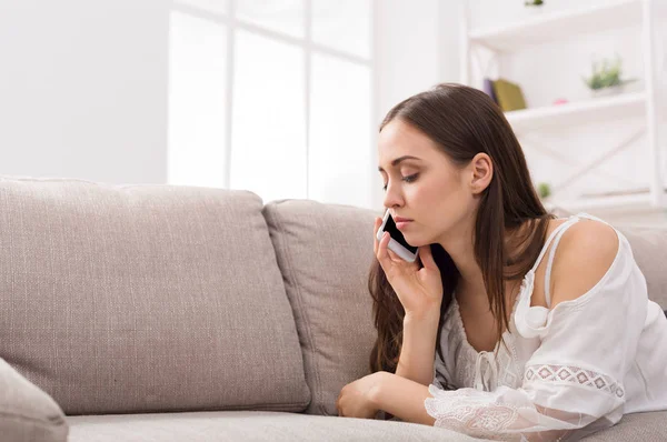 Young girl talking on mobile lying on sofa — Stock Photo, Image