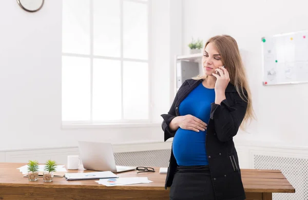 Pregnant business woman talking on phone at office — Stock Photo, Image