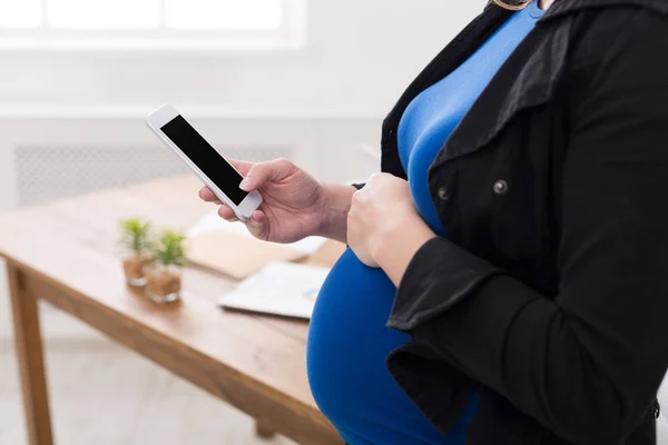 Mujer embarazada irreconocible con teléfono inteligente — Foto de Stock