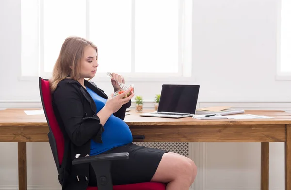 Embarazada mujer de negocios comiendo ensalada en la oficina — Foto de Stock