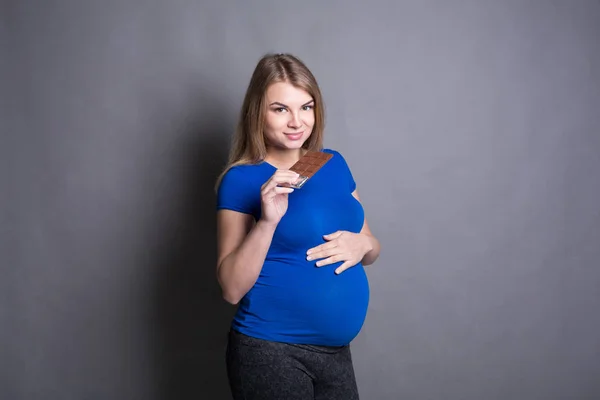 Mulher grávida gostando de comer barra de chocolate — Fotografia de Stock