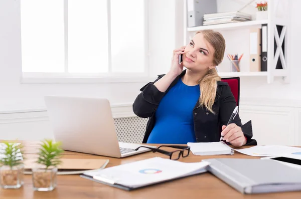 Pregnant business lady at work talking on phone