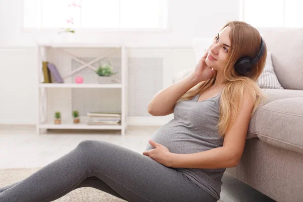 Kulaklıkla müzik dinleyen hamile kadın. — Stok fotoğraf