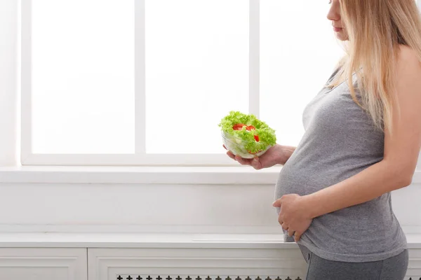 Молодая беременная женщина ест свежий зеленый салат — стоковое фото