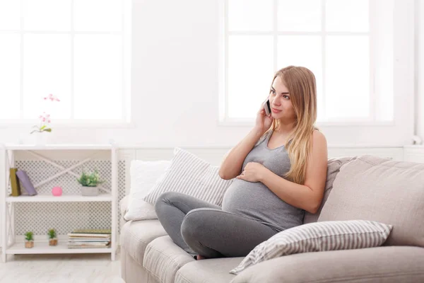 Mujer embarazada sonriente hablando en su smartphone — Foto de Stock