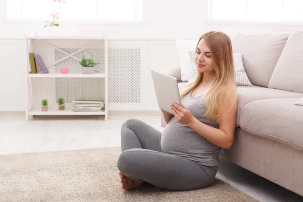 Happy pregnant woman using digital tablet.