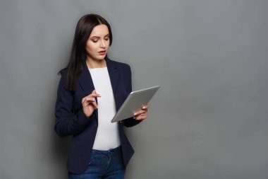 Tablet gri arka plan üzerinde konsantre kadınla