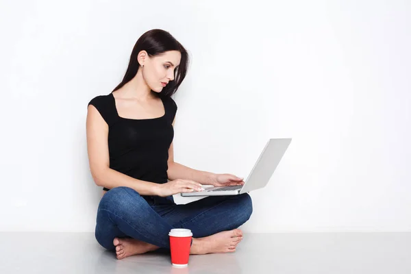 Frau sitzt mit Laptop auf dem Studioboden — Stockfoto