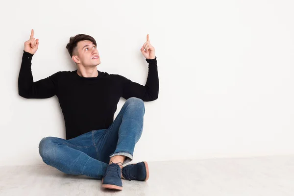 Joven apunta hacia arriba en el fondo del estudio blanco . —  Fotos de Stock