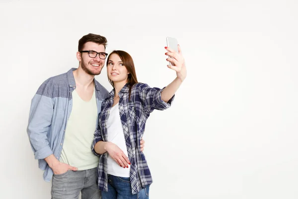 Feliz pareja casual haciendo selfie en el teléfono inteligente, aislado — Foto de Stock