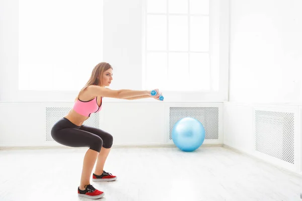 Young beautiful woman in sportswear doing squat — Stock Photo, Image