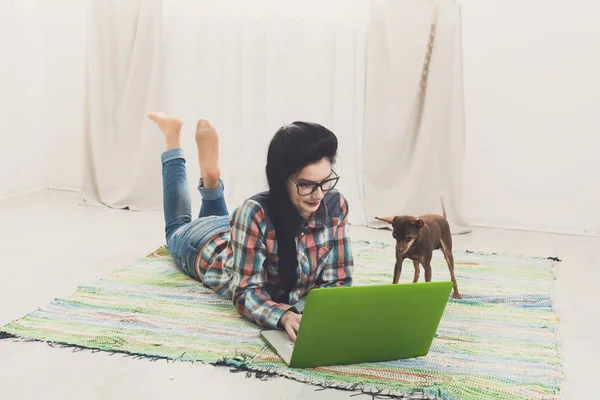 Young girl on floor with laptop and dog