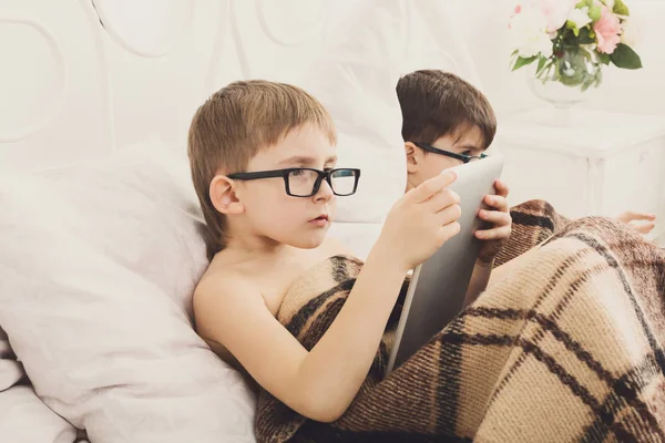 Dos muchachos juegan en el portátil y la tableta con el perro en la cama — Foto de Stock