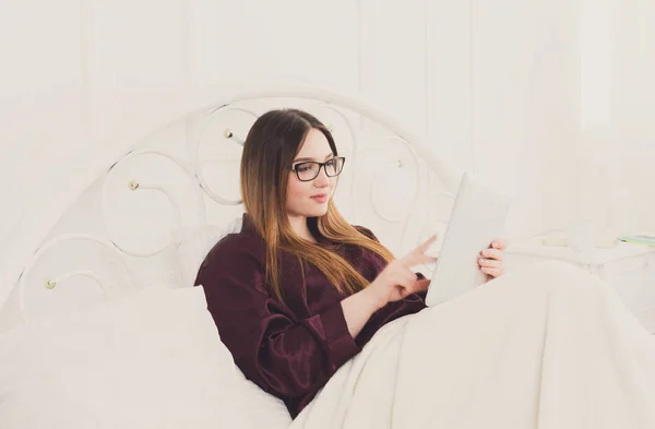 Женщина читает с планшета ПК в постели, копировать пространство — стоковое фото