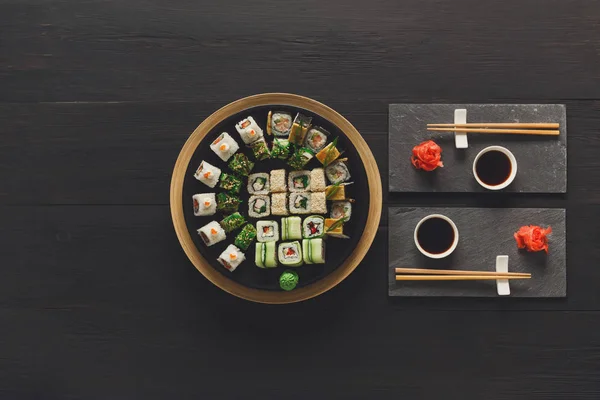 Set de sushi maki y rollos en madera rústica negra, vista superior — Foto de Stock