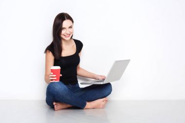 Stüdyo katta oturan dizüstü kullanan kadın