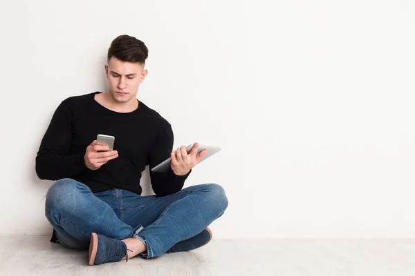 Чоловік навчається онлайн, сидить з ноутбуком і використовує мобільний телефон — стокове фото