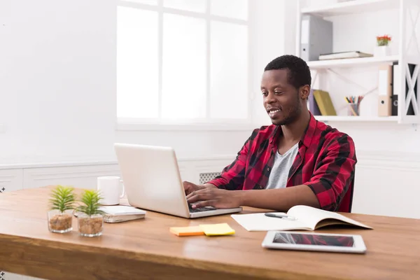 Sonriente negro feliz hombre de negocios en la oficina informal, trabajar con el ordenador portátil —  Fotos de Stock