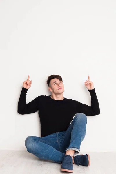 Joven apunta hacia arriba en el fondo del estudio blanco . — Foto de Stock