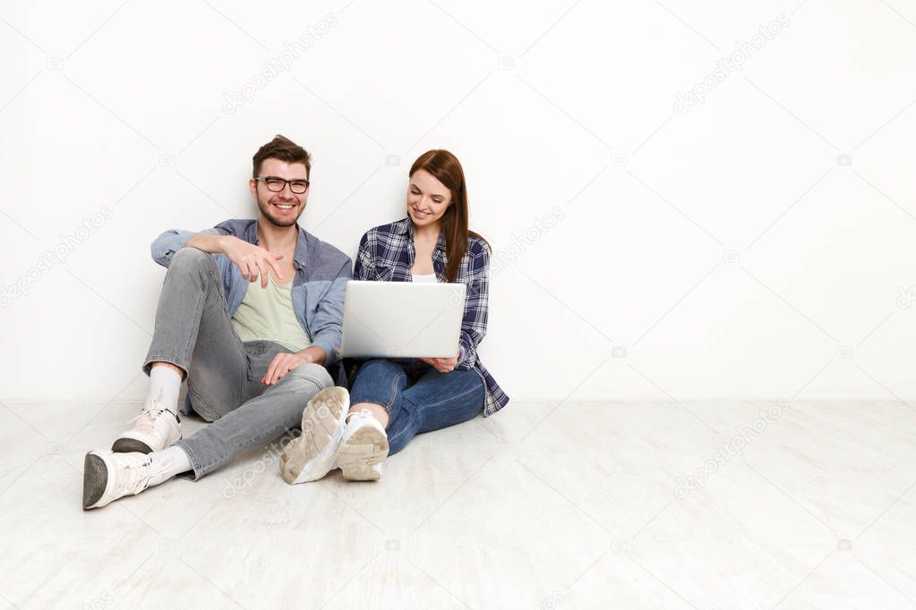 Smiling couple web-surfing on laptop, studio shot