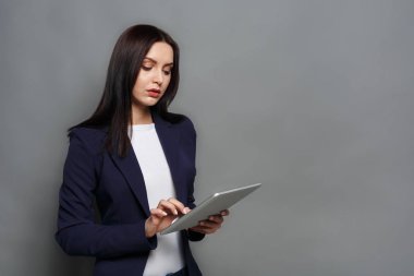 Tablet gri arka plan üzerinde konsantre kadınla