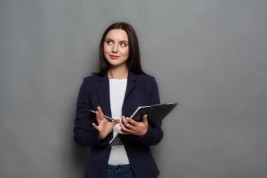 Gri arka plan üzerinde not defteri ile kendine güvenen kadın