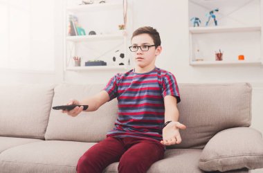 Televizyon izlerken, uzaktan kumanda ile genç çocuk