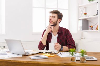 Modern beyaz ofis içinde laptop ile dalgın genç işadamı