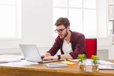 Modern beyaz ofis içinde laptop ile çalışan dalgın genç işadamı