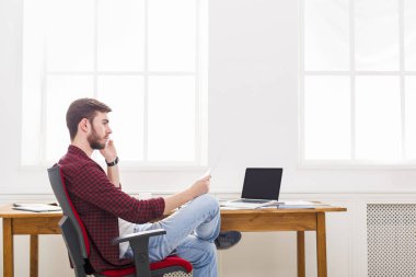 Konsantre genç işadamı modern beyaz ofiste bir telefon konuşma vardır